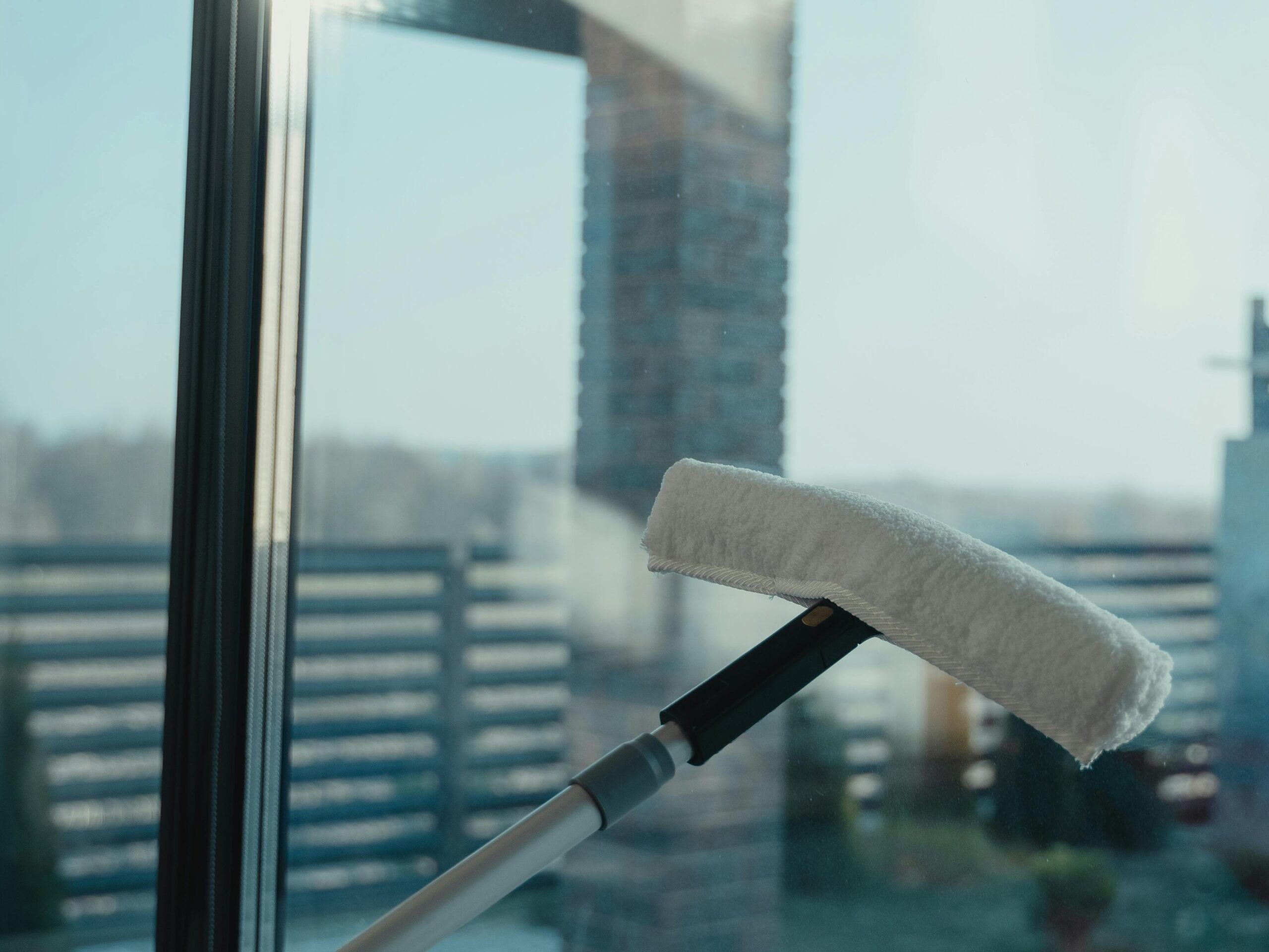 A modern cleaning tool used to clean a large glass window with a clear outdoor view.
